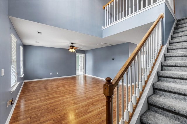 stairs with hardwood / wood-style flooring, ceiling fan, and a towering ceiling