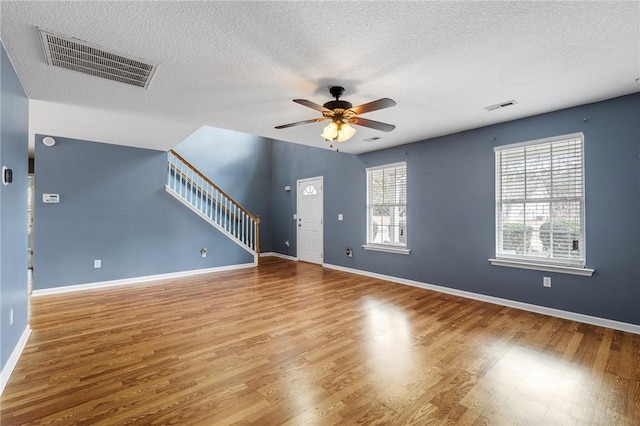 unfurnished living room featuring hardwood / wood-style flooring, ceiling fan, and a textured ceiling