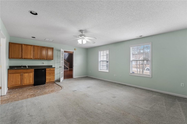 kitchen with light colored carpet, black dishwasher, sink, and a textured ceiling