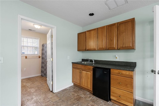 kitchen with fridge, sink, and a textured ceiling