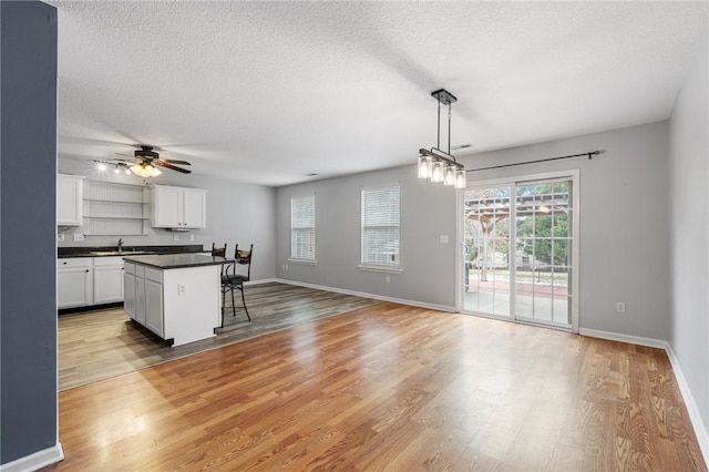 kitchen with pendant lighting, sink, white cabinetry, light hardwood / wood-style floors, and a kitchen bar