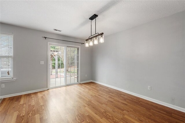 unfurnished dining area featuring a textured ceiling and light hardwood / wood-style flooring