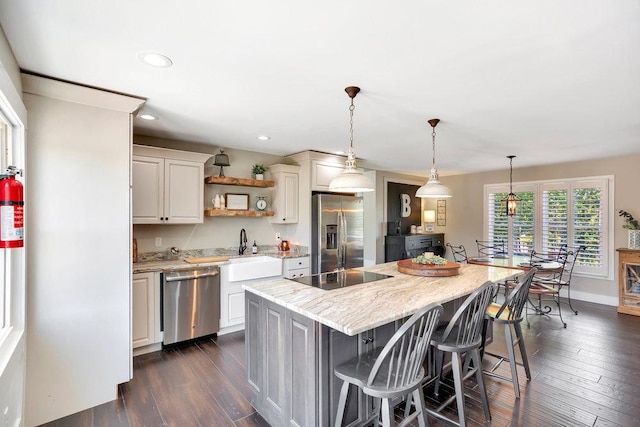 kitchen featuring appliances with stainless steel finishes, sink, a kitchen breakfast bar, a center island, and light stone countertops