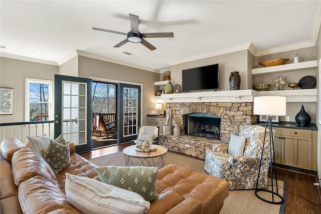 living room with dark wood-type flooring, ceiling fan, a fireplace, ornamental molding, and french doors