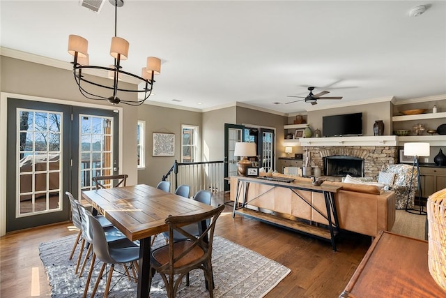 dining room featuring hardwood / wood-style flooring, crown molding, and a fireplace