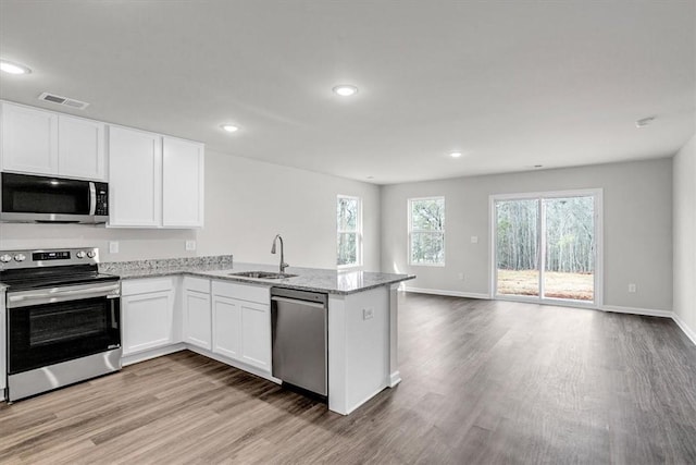 kitchen featuring sink, light hardwood / wood-style flooring, stainless steel appliances, white cabinets, and kitchen peninsula