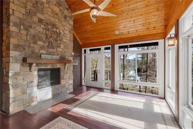 interior space featuring ceiling fan, lofted ceiling, a stone fireplace, and wooden ceiling