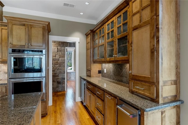 kitchen featuring double oven, decorative backsplash, and stone counters