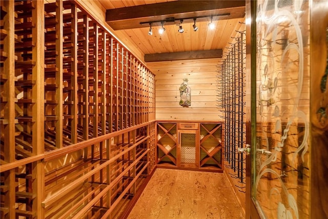 wine room featuring hardwood / wood-style flooring, beamed ceiling, wooden walls, and wooden ceiling