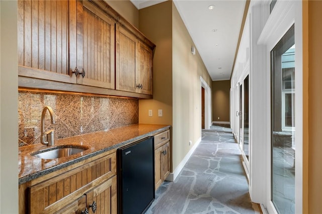 kitchen featuring dishwasher, sink, dark stone countertops, and decorative backsplash