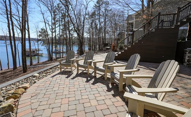 view of patio featuring a water view and stairs