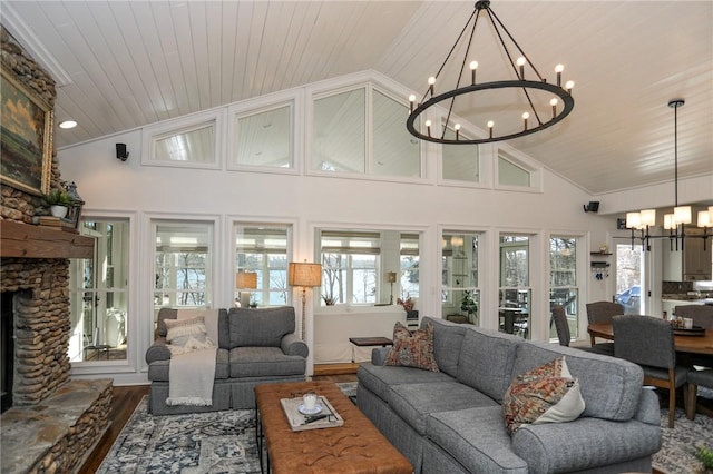 living area with wood ceiling, wood finished floors, a stone fireplace, high vaulted ceiling, and a notable chandelier