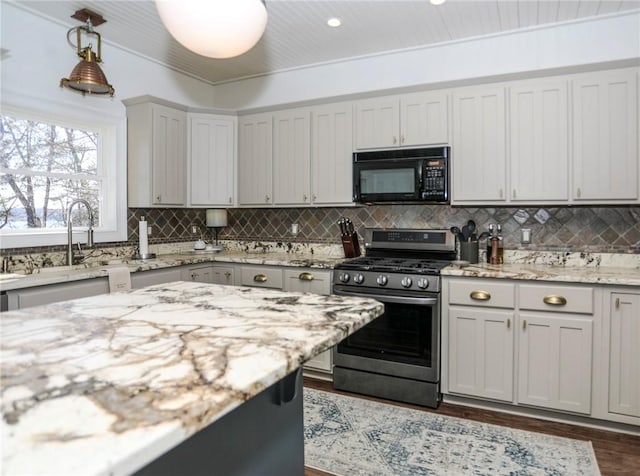 kitchen with black microwave, decorative light fixtures, a sink, decorative backsplash, and stainless steel range with gas stovetop