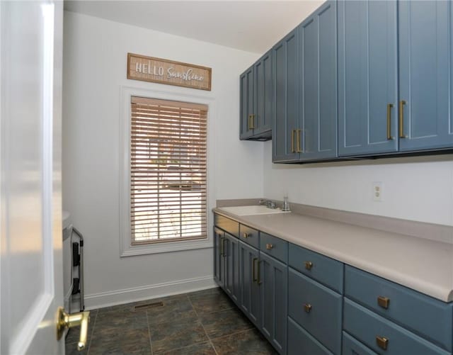 kitchen featuring blue cabinetry, light countertops, and a sink