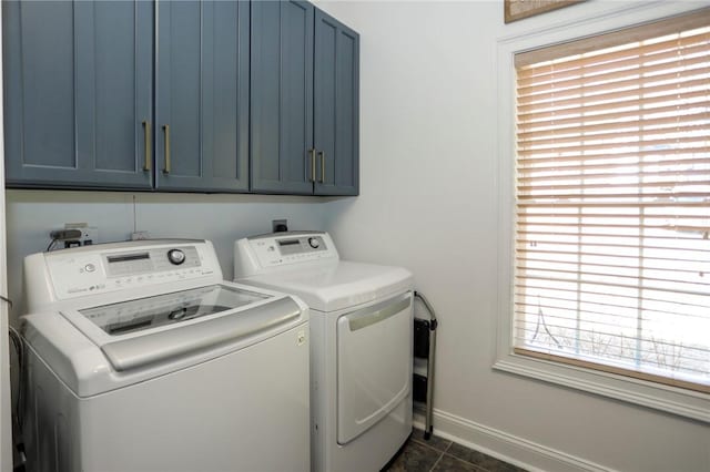 laundry area featuring separate washer and dryer, cabinet space, and baseboards