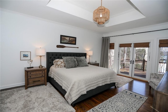 bedroom with a raised ceiling, ornamental molding, wood finished floors, access to outside, and french doors