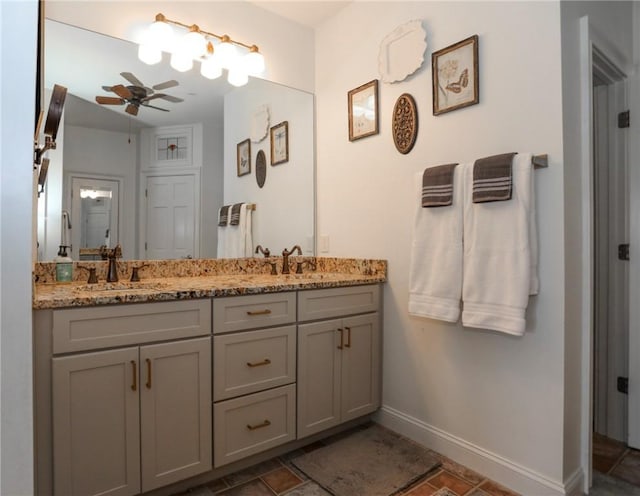 full bathroom featuring ceiling fan, a sink, baseboards, and double vanity