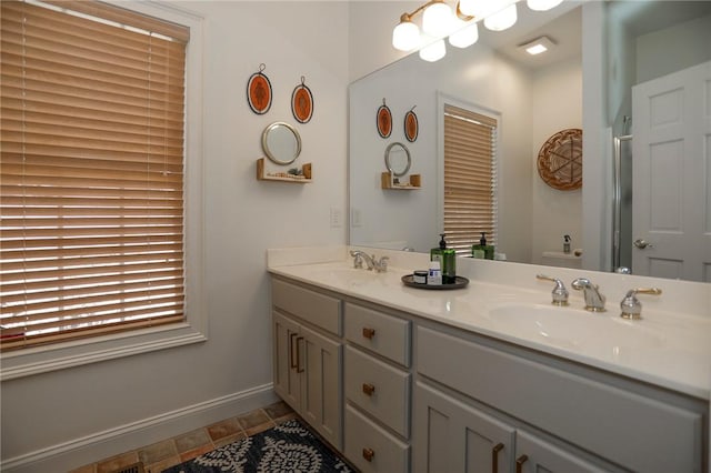 bathroom featuring double vanity, a notable chandelier, baseboards, and a sink