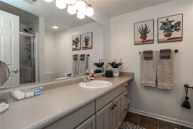 full bath featuring toilet, a stall shower, vanity, and baseboards