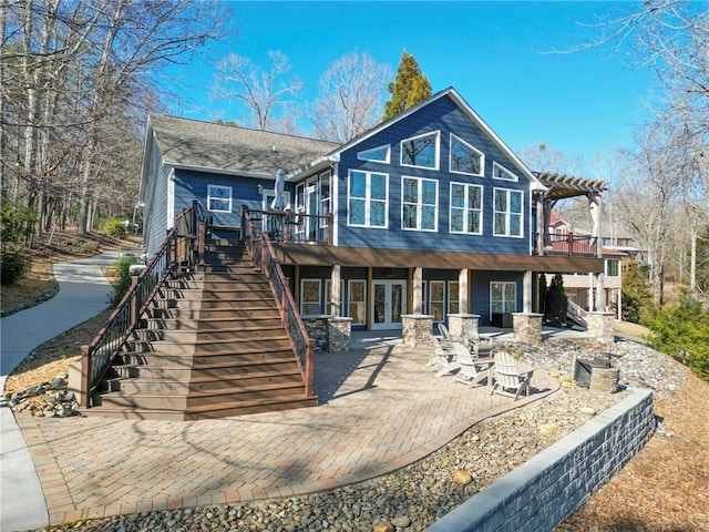 back of property with french doors, stairway, a wooden deck, a patio area, and a pergola