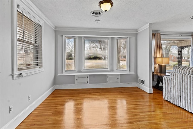 interior space with ornamental molding, light hardwood / wood-style floors, and a textured ceiling