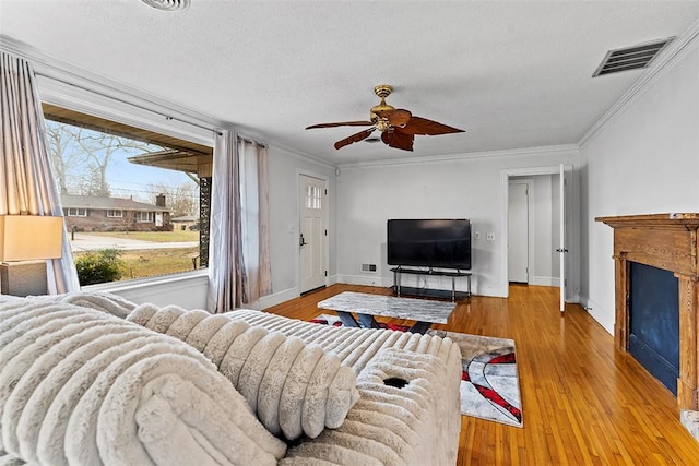 living room with ornamental molding, light hardwood / wood-style floors, and a textured ceiling