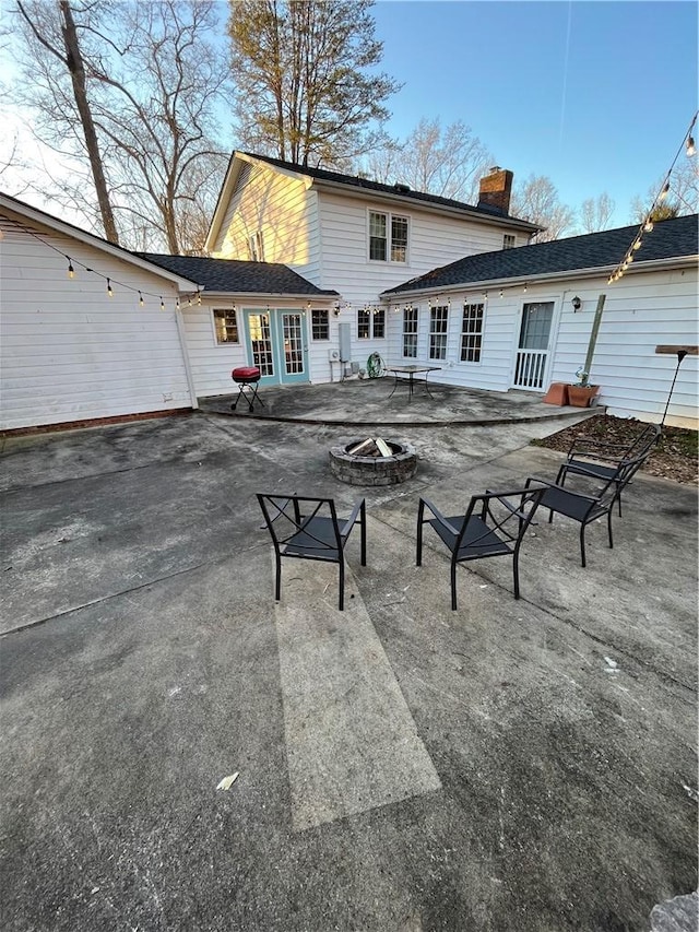 back of property featuring french doors, a patio area, and a fire pit