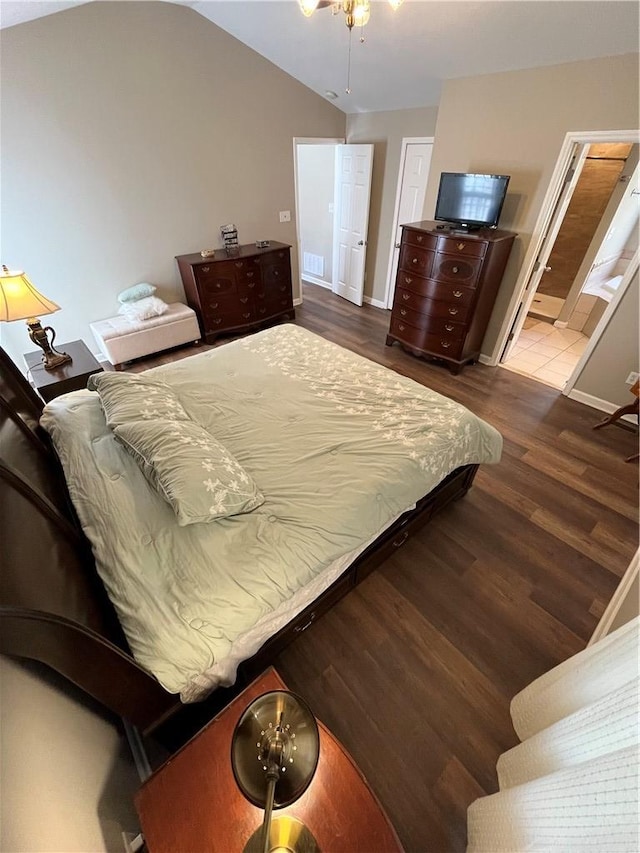 bedroom featuring lofted ceiling, dark wood-type flooring, and ensuite bathroom