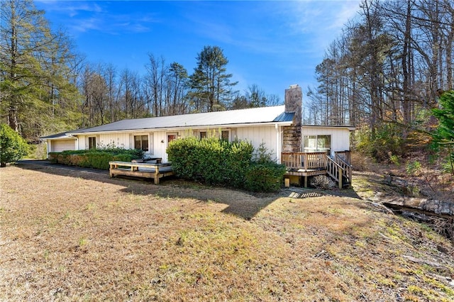 back of house featuring a garage, a lawn, and a deck