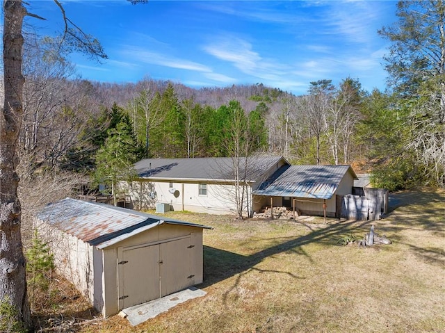 back of property featuring a storage unit and a lawn