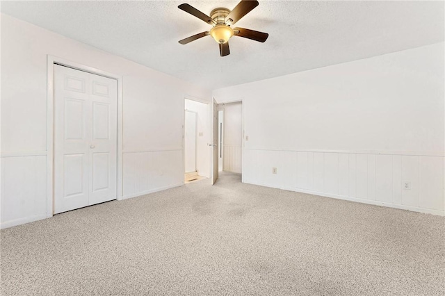 unfurnished bedroom featuring ceiling fan, carpet flooring, a closet, and a textured ceiling