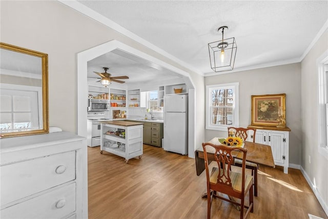 kitchen with decorative light fixtures, sink, white cabinets, white appliances, and light hardwood / wood-style flooring