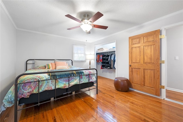 bedroom featuring wood-type flooring, a textured ceiling, crown molding, and a closet