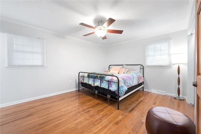 bedroom with crown molding, ceiling fan, wood-type flooring, and a textured ceiling