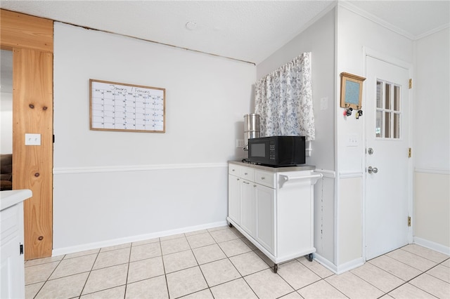 kitchen featuring white cabinetry, crown molding, a textured ceiling, and light tile patterned floors