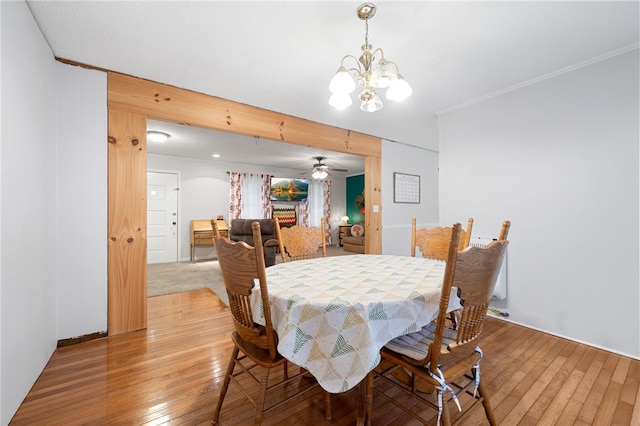 dining area with ceiling fan with notable chandelier, ornamental molding, and hardwood / wood-style floors