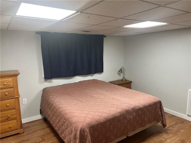 bedroom featuring a paneled ceiling and dark hardwood / wood-style floors