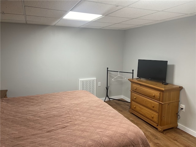 bedroom featuring wood-type flooring and a drop ceiling