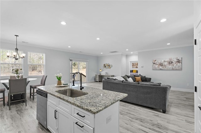 kitchen featuring pendant lighting, sink, dishwasher, white cabinetry, and a center island with sink