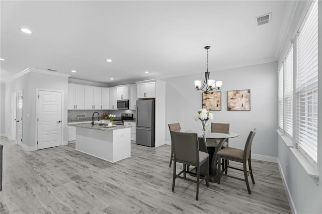 kitchen with white cabinetry, ornamental molding, an island with sink, stainless steel appliances, and light stone countertops