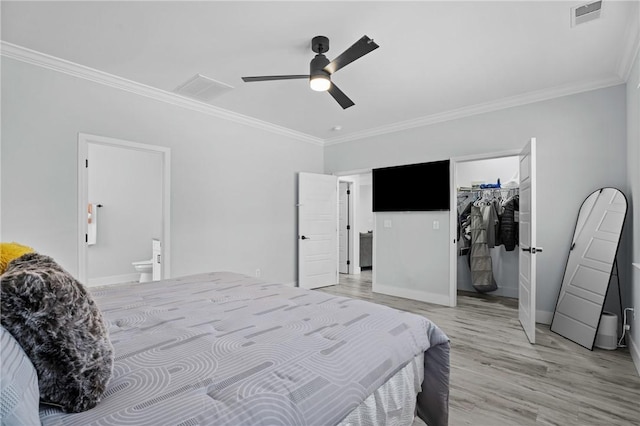 bedroom featuring wood-type flooring, ornamental molding, ceiling fan, ensuite bath, and a closet