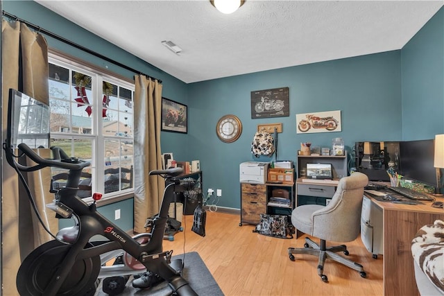 office area featuring baseboards, visible vents, a textured ceiling, and light wood finished floors