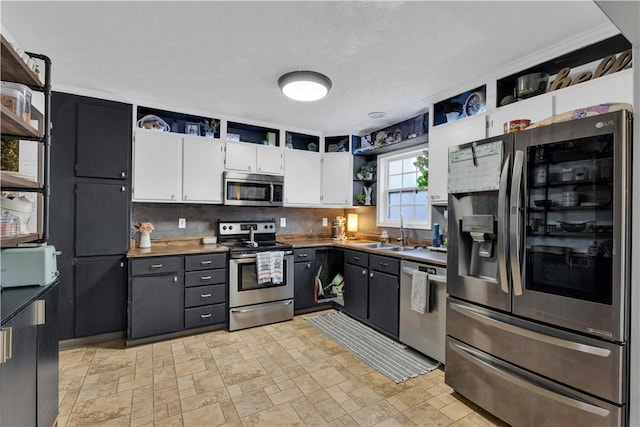 kitchen with a sink, white cabinetry, appliances with stainless steel finishes, backsplash, and open shelves