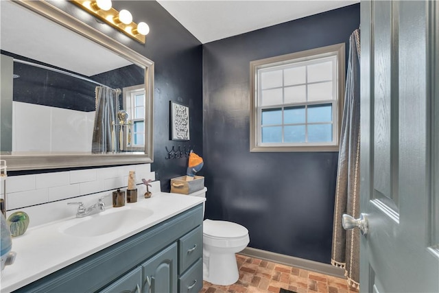 full bathroom featuring brick floor, toilet, vanity, baseboards, and a shower with curtain