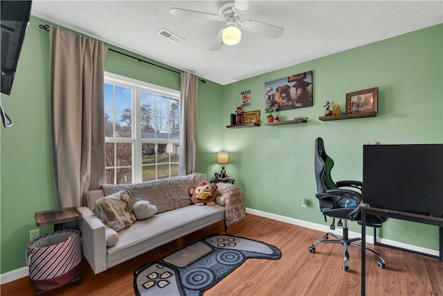 office area with a ceiling fan, wood finished floors, visible vents, and baseboards