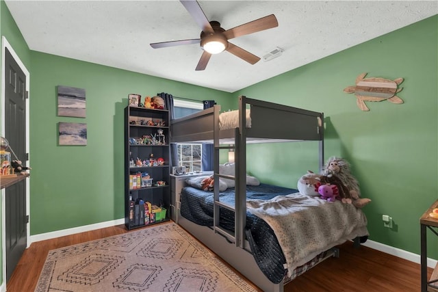 bedroom featuring visible vents, wood finished floors, a ceiling fan, and baseboards