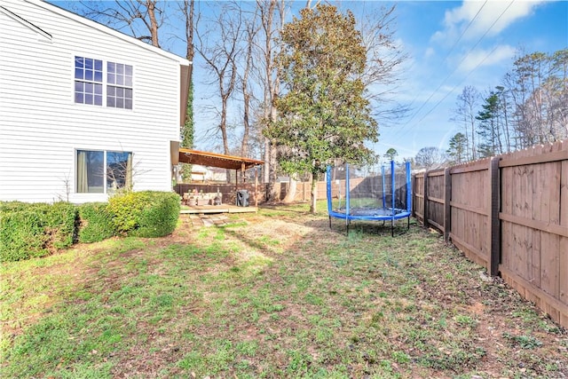 view of yard with a fenced backyard, a trampoline, and a deck