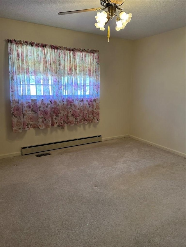 carpeted spare room with baseboards, visible vents, a ceiling fan, a textured ceiling, and a baseboard heating unit