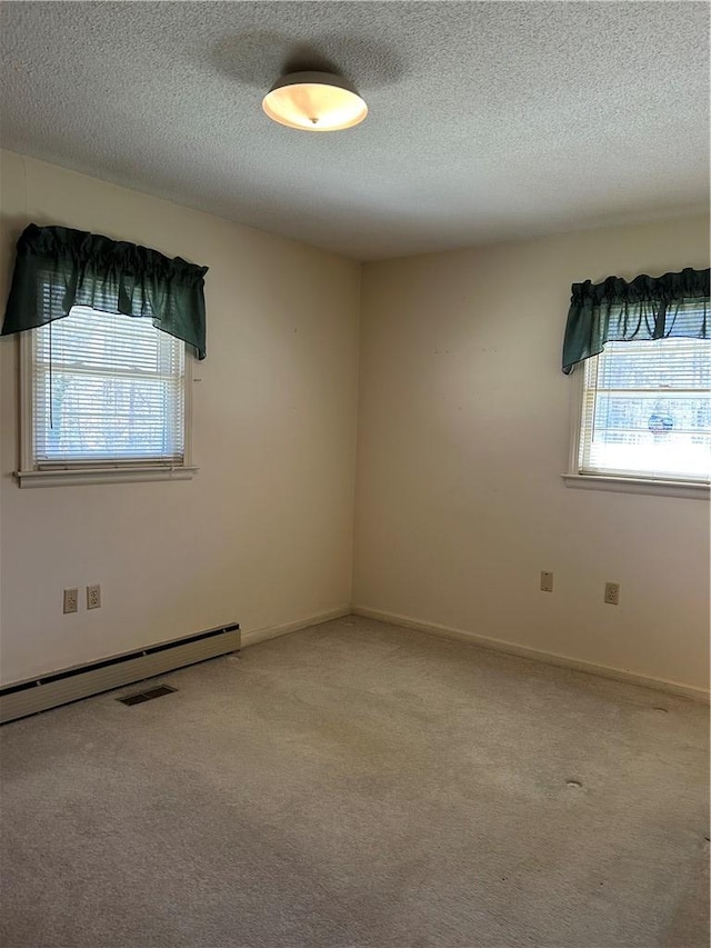 carpeted spare room featuring a baseboard heating unit, a textured ceiling, and baseboards