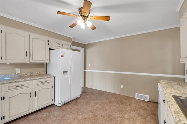 kitchen with sink, white fridge with ice dispenser, crown molding, ceiling fan, and white cabinets